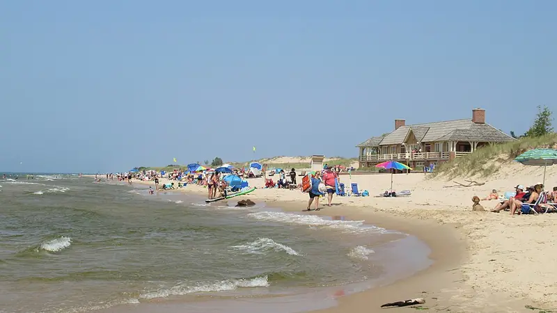 Sandy Lake Michigan beach with visitors and a beach house