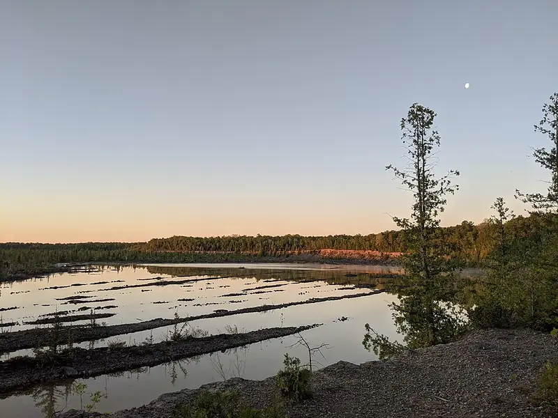 Flooded old quarry at sunrise with trees on the rim