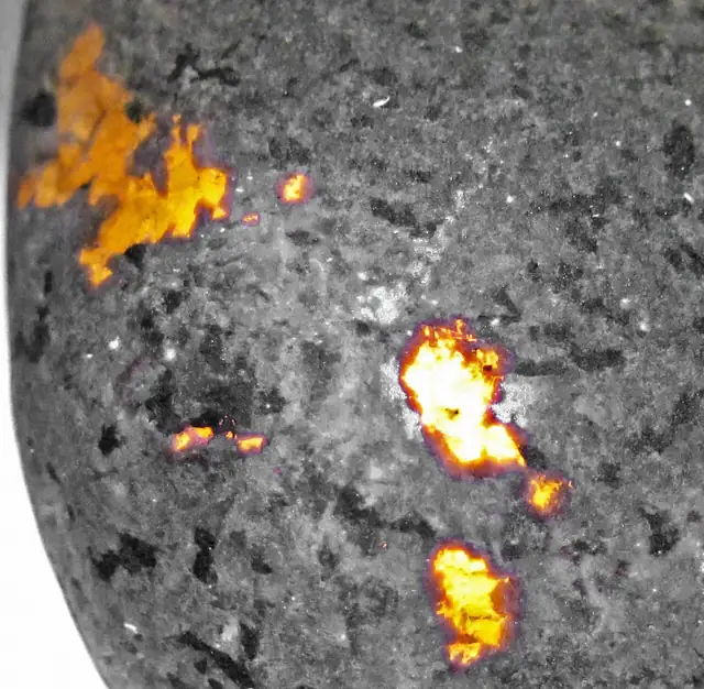 Yooperlite under UV light, with orange-glowing sodalite, Lake Superior shoreline, Upper Peninsula